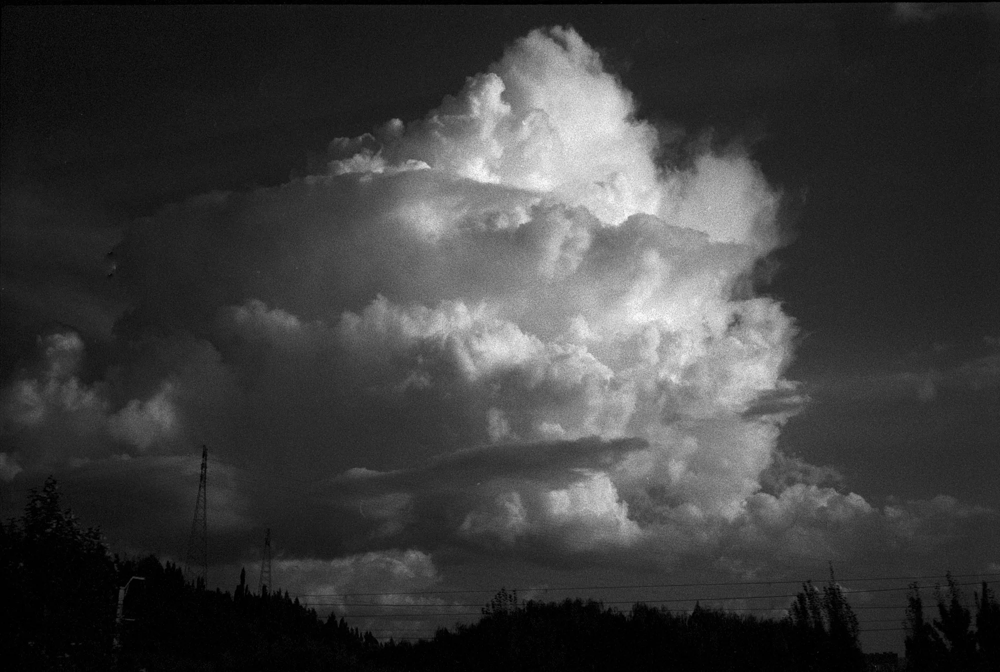 A towering bright cloud rises above a dark horizon in Yunnan.