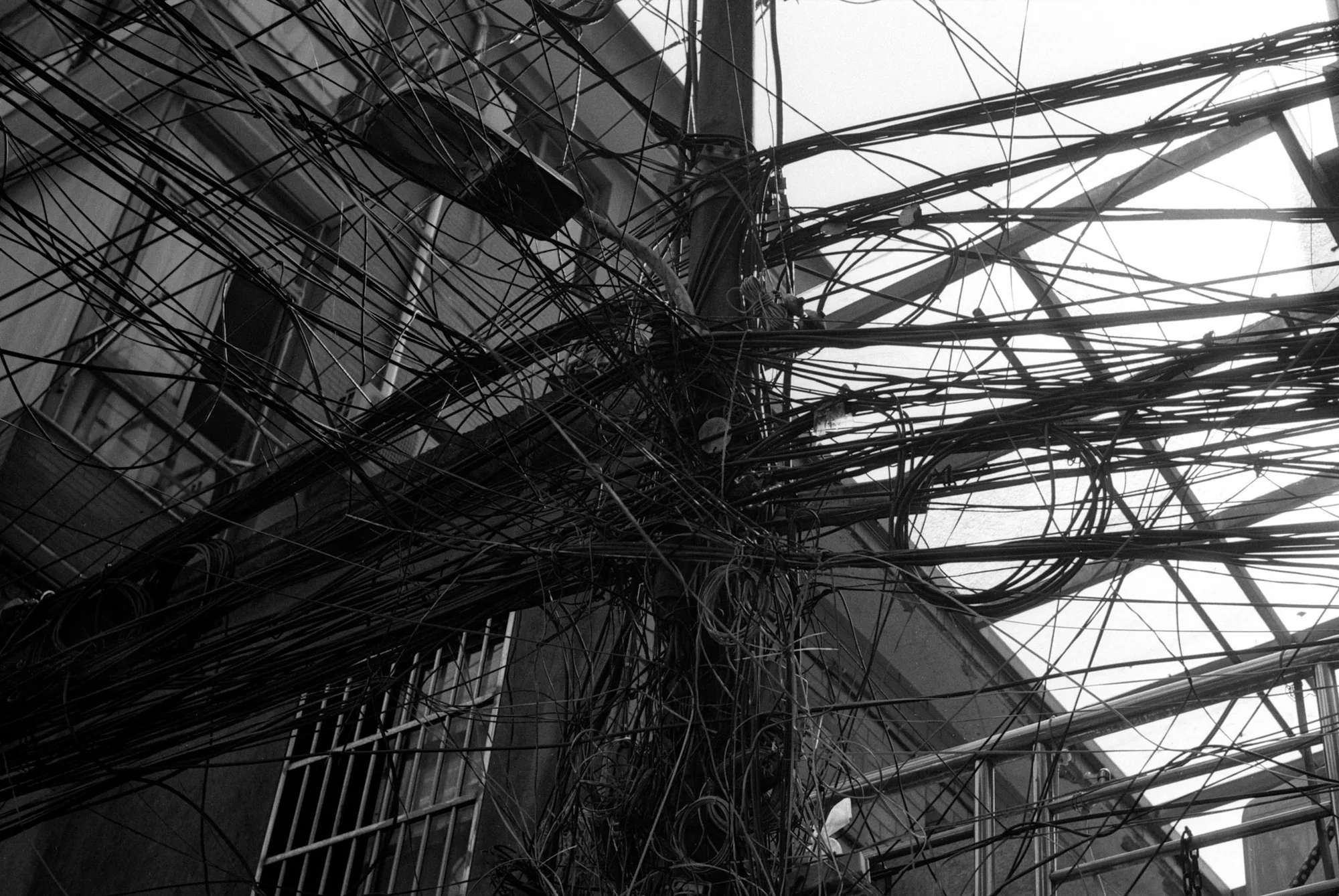 A dense web of utility wires crosses above the windows and roof of an old building.