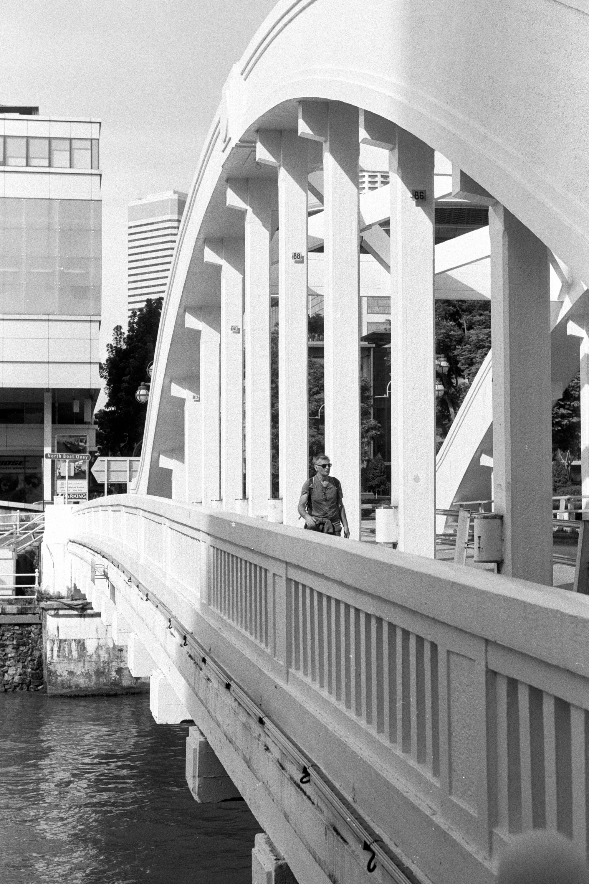 Repeating white railings curve along a bridge above the water.