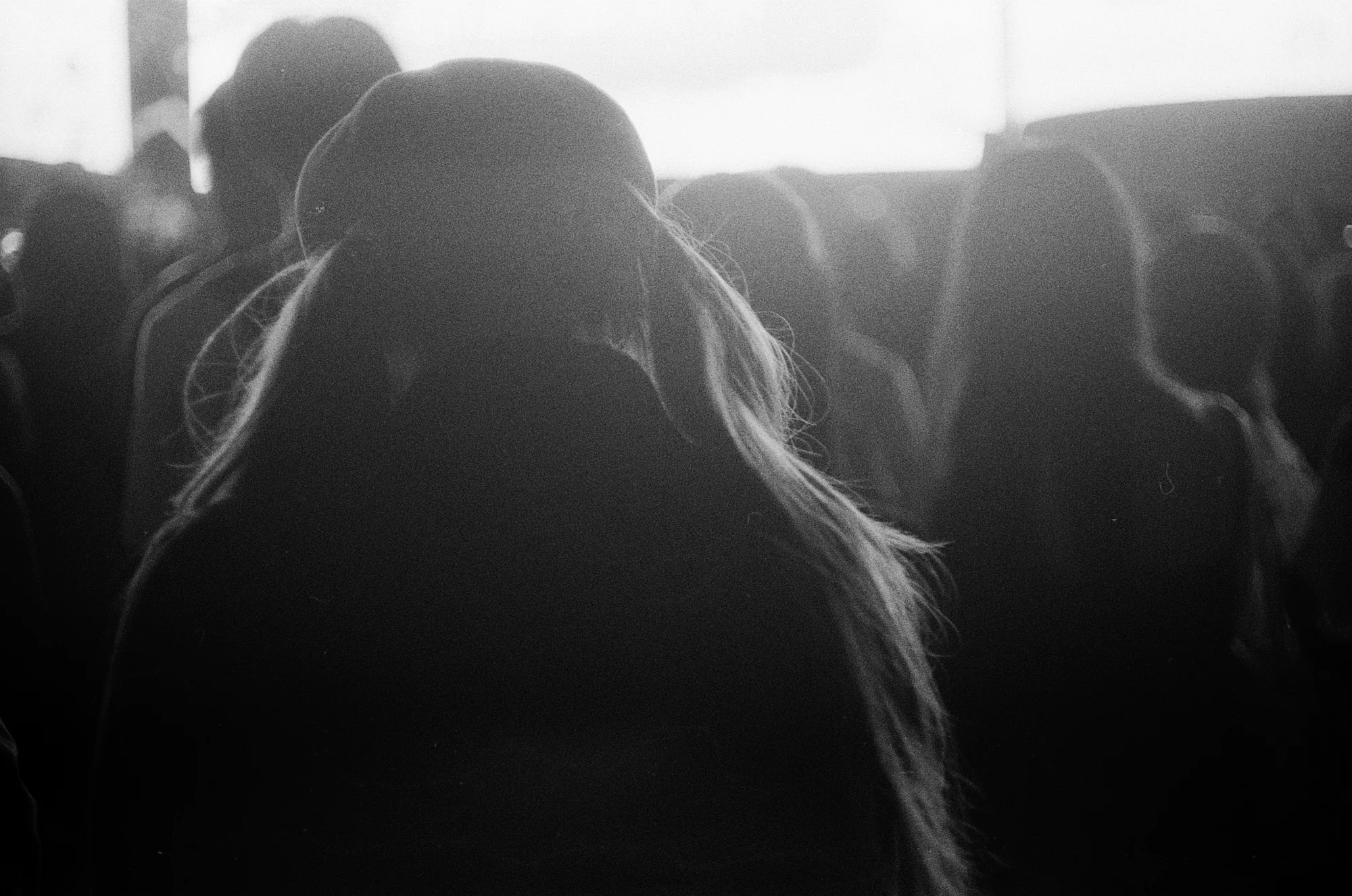 Two figures lean close together in strong light, their faces mostly in silhouette.