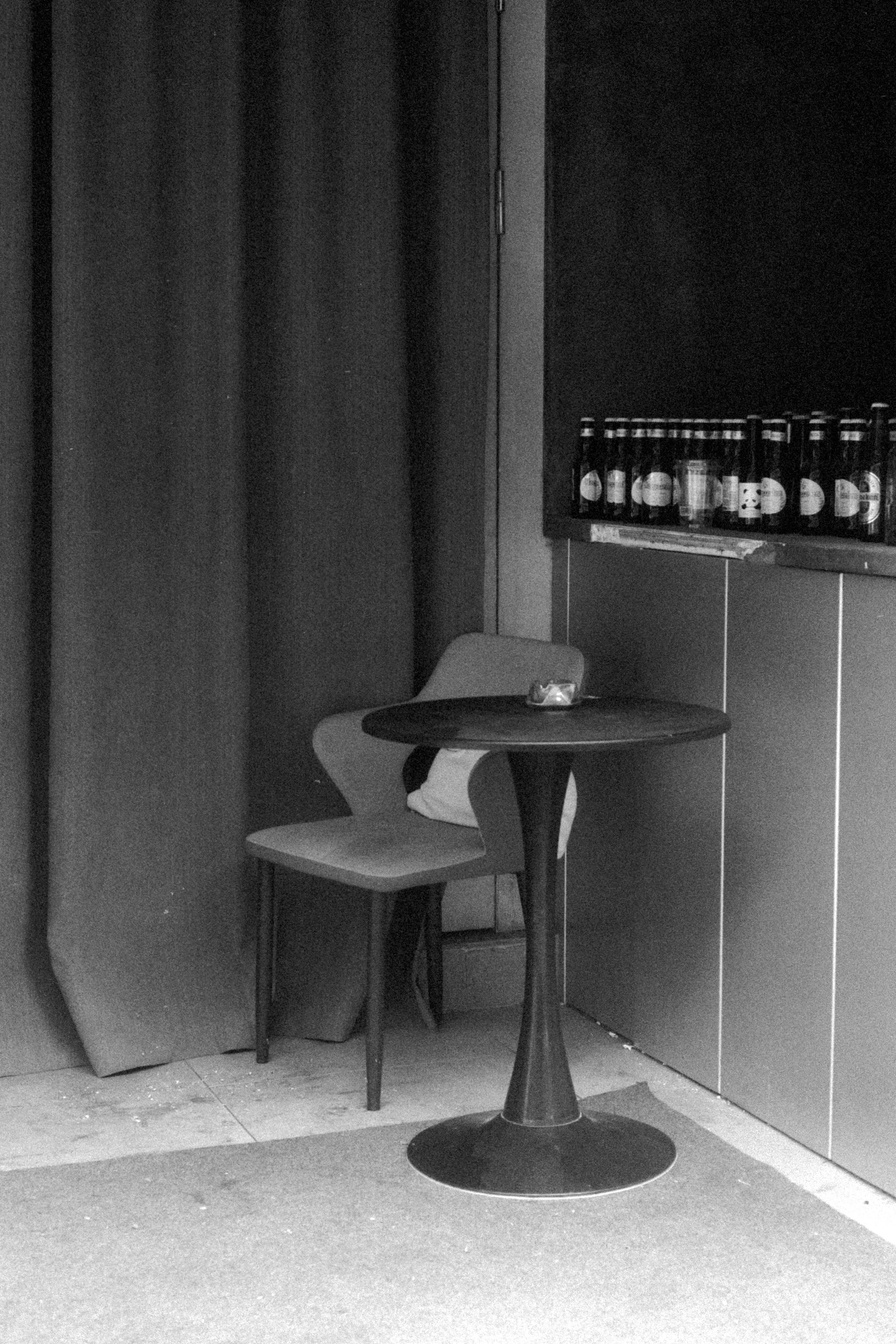 A small round table and single chair stand inside a dark recessed doorway.